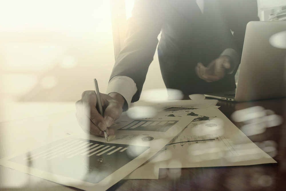 business documents on office table with smart phone and digital tablet and graph business diagram and man working in the background-1